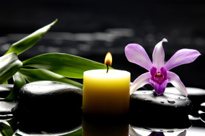 aromatherapy candle and bright orchid on zen stones
