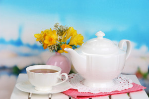 White tea set with yellow flowers and blue sky background