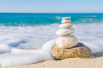 ocean with foam and stacked rocks on a beach, mindfulness meditation