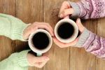 women's hands holding coffee cups