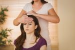 Young woman having a reiki treatment in therapy room