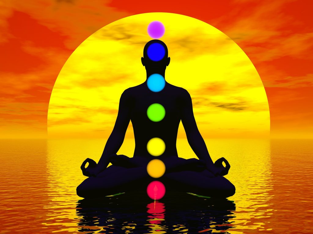 Silhouetted person in lotus pose with chakras shown