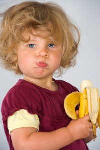 little blond girl eating a banana at a shelter for homeless people