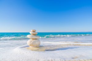 ocean foam on beach with stacked white rocks in a Zen formation