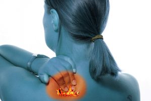 head and shoulder view of woman rubbing her back with orange spot indicating back pain