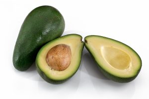 a whole avocado, and one cut in half with seed showing - great source of magnesium to help prevent cramps