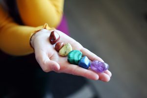 hand holding stones of each chakra color. Image by Sharon McCutcheon